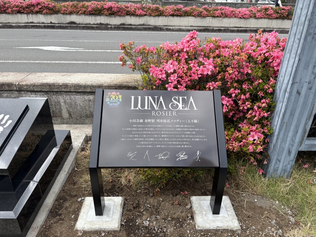 花に囲まれて立つLUNA SEAモニュメントの案内板